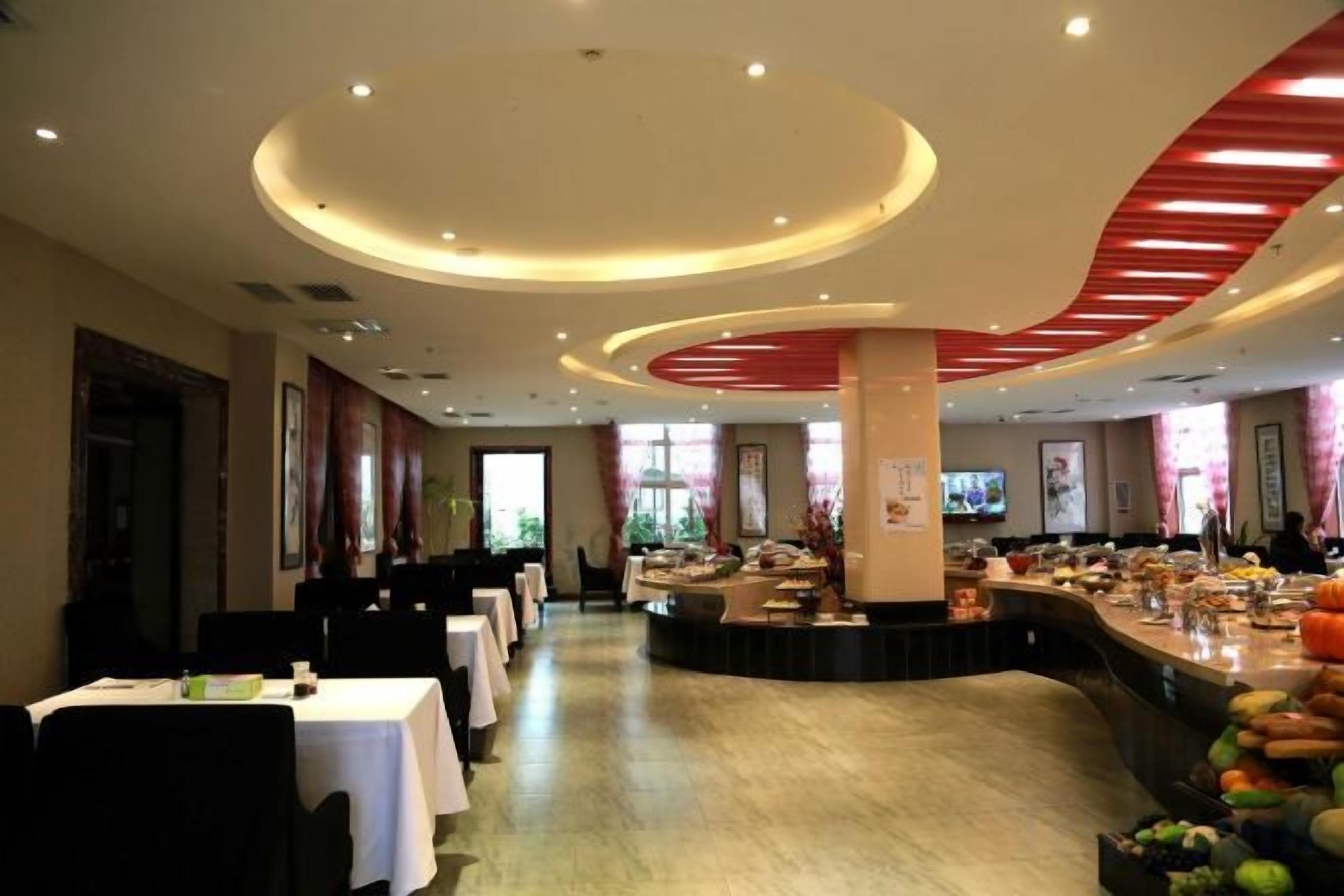 Een restaurantgedeelte in een hotel met ronde tafels, een bar in het midden en uitzicht op het omliggende landschap.