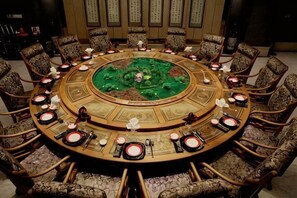 Une table ronde avec un plateau vert, entourée de chaises à motifs.