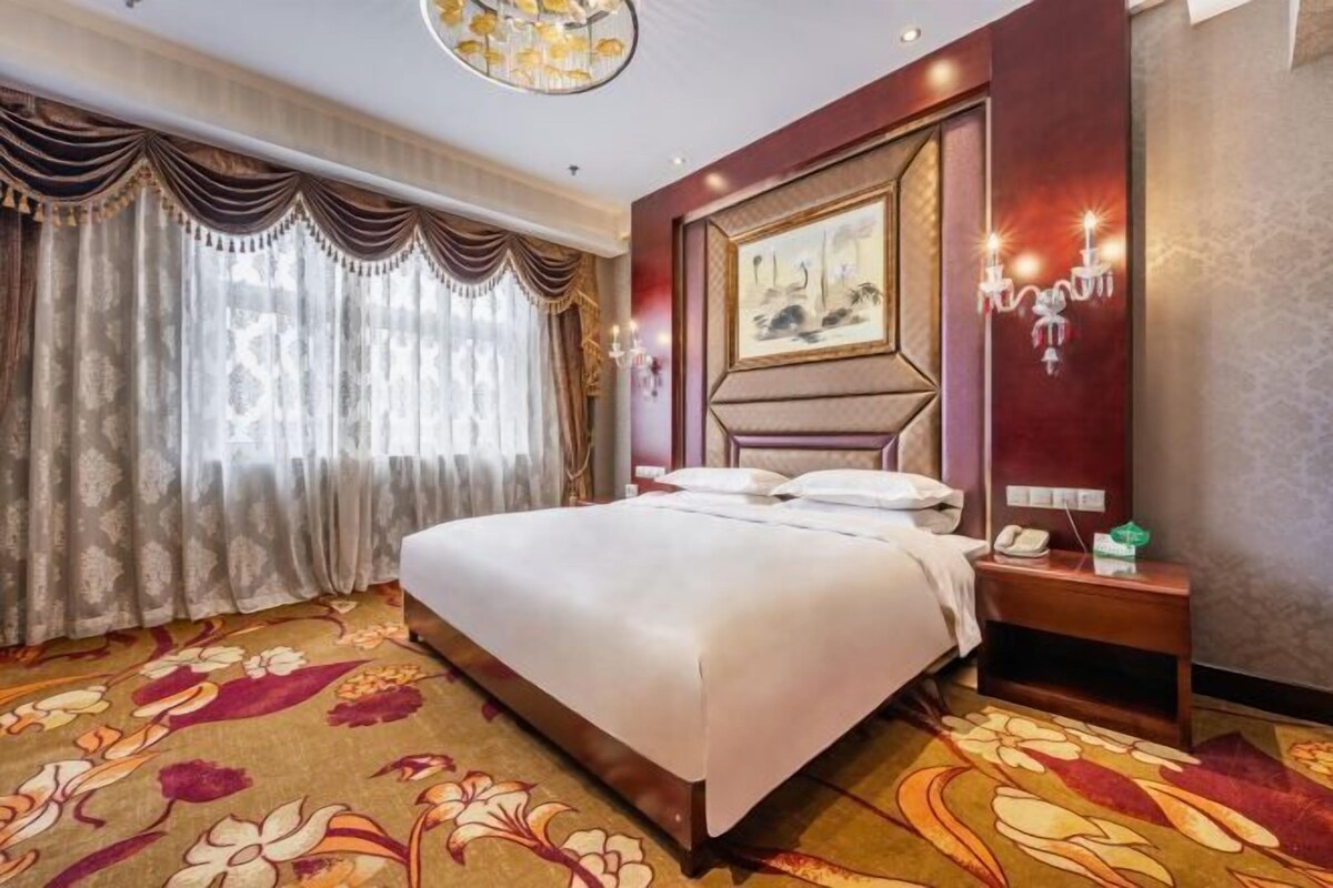 Une chambre d’hôtel avec un grand lit, une table de chevet avec un téléphone et un tableau au mur.