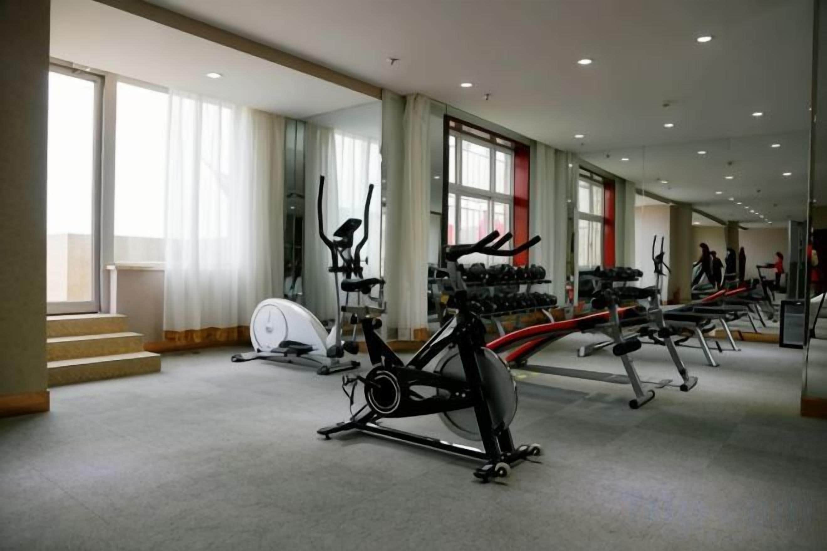 A gym with cardio machines, weight benches, and dumbbells.