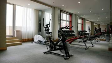 A gym with cardio machines, weight benches, and dumbbells.