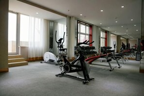 Ein Fitnessstudio mit Cardiogeräten, Gewichte-Bänken und Kurzhanteln.