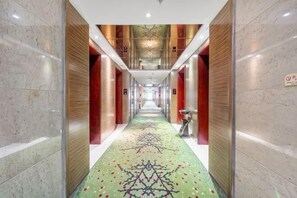 Ein Hotelgang mit Teppichmuster, Holzvertäfelung und Marmorwänden.
