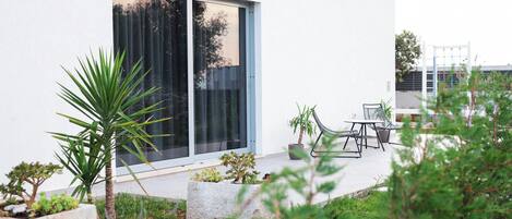 Une maison moderne dotée d’une grande porte-fenêtre coulissante, d’un espace salon extérieur et d’un jardin bien entretenu.