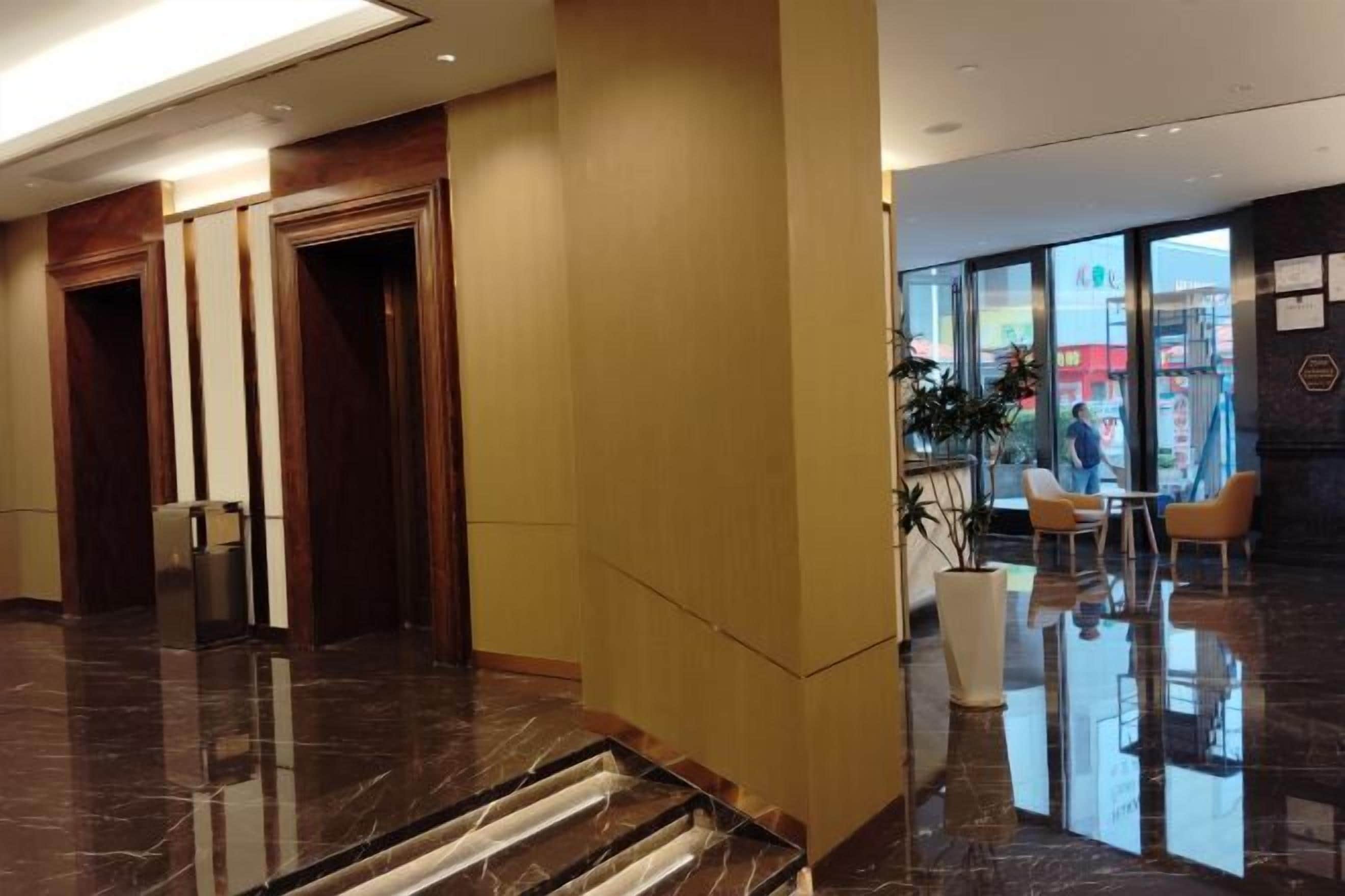 Un hall d’hôtel avec un sol en marbre, un comptoir d’accueil et un espace détente avec des fauteuils.