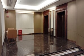 A hotel lobby with a marble floor, a reception desk, and a wooden door. - Huangjiang Holiday Hotel (Dongguan)