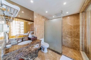 Een moderne badkamer met een marmeren wastafel, toilet en een douchecabine van glas.