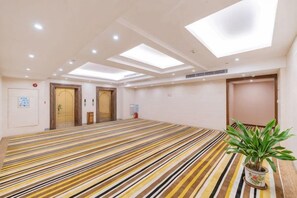 A hotel room with a striped carpet, a potted plant, and a ceiling with skylights. - Huangjiang Holiday Hotel (Dongguan)