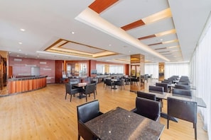 Un restaurant spacieux avec de nombreuses tables et chaises, un bar et une cuisine située à l’arrière.