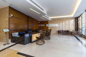 A reception area with a marble counter, seating, and a large window. - Huangjiang Holiday Hotel (Dongguan)