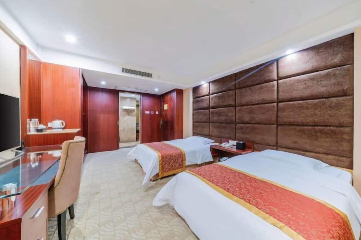 Une chambre d’hôtel avec deux lits, un bureau et une télévision.