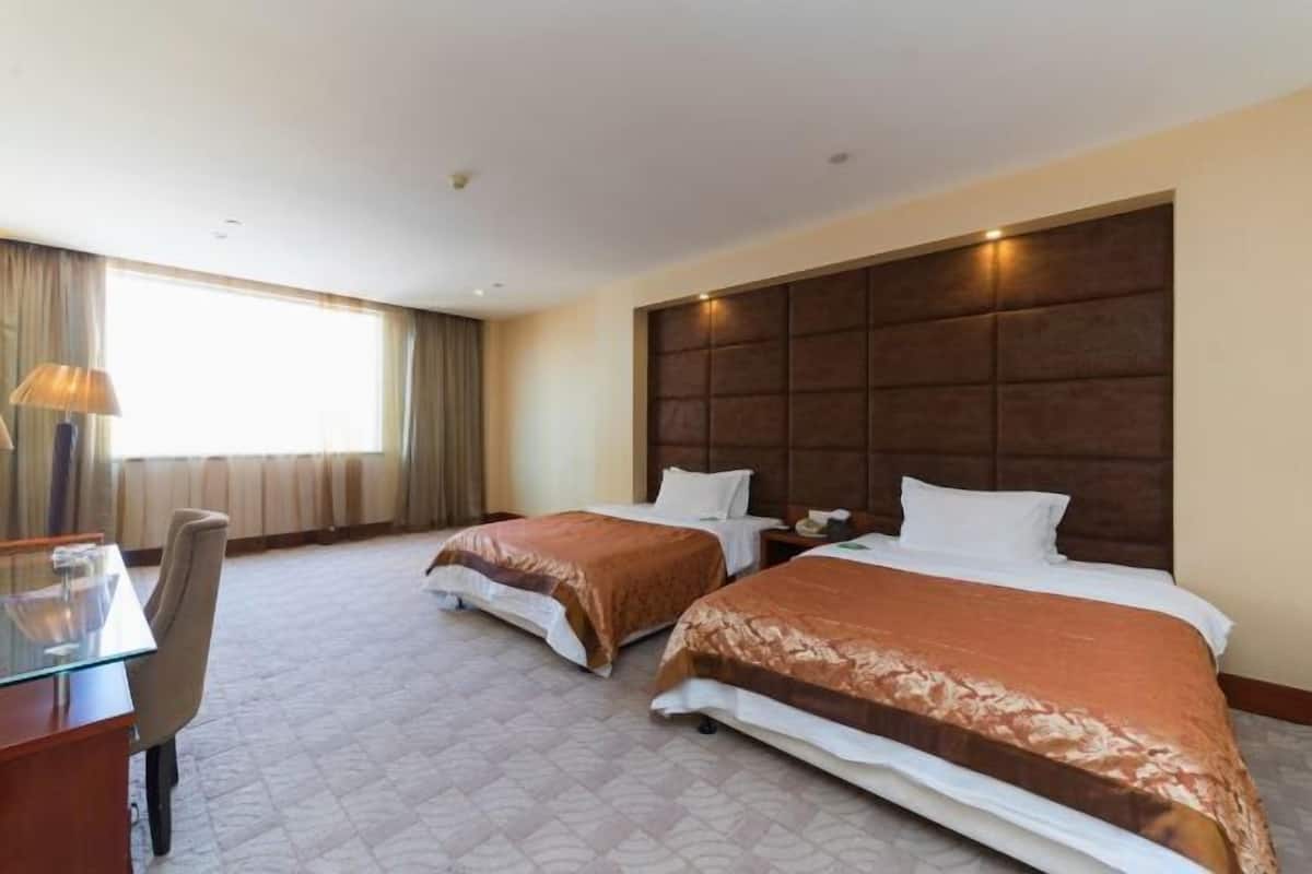 Une chambre d’hôtel avec deux lits, un bureau et une chaise.