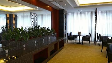 Un vestíbulo de hotel con mostrador de recepción, zona de estar y grandes ventanales.
