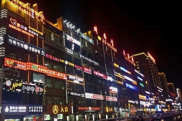A brightly lit commercial building with multiple illuminated signs and advertisements. - Apple Apartment (Yanji)