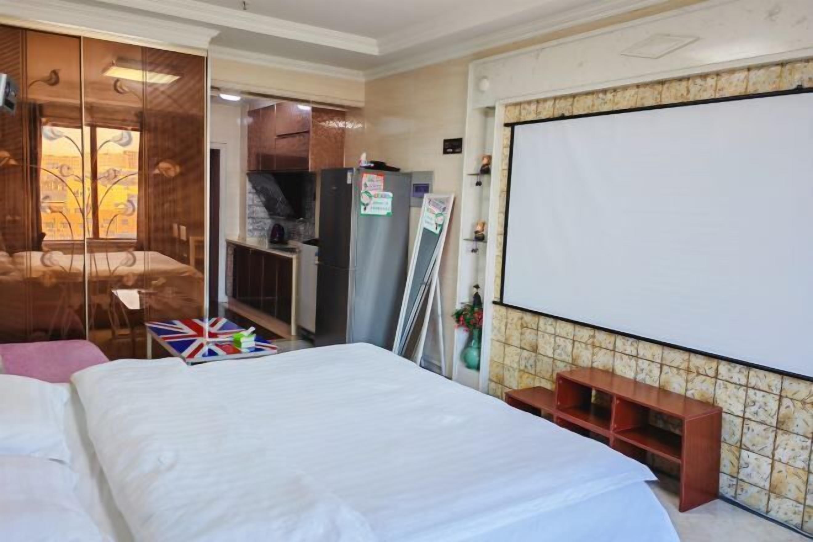Quarto de hotel com cama, escrivaninha, guarda-roupa e televisão.