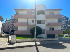 A multi-story residential building with balconies, a central cylindrical structure, and a paved courtyard. - Charming duplex apartment with a terrace and a view of the pool, 200 m from the beach (Portimão)