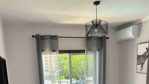 Habitación de hotel con cama, escritorio, silla, balcón con vistas y aire acondicionado.