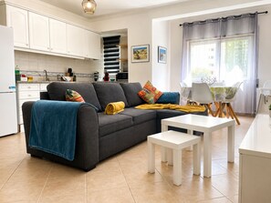 A modern living room with a sofa, a coffee table, and a dining area with chairs. - Charming duplex apartment with a terrace and a view of the pool, 200 m from the beach (Portimão)