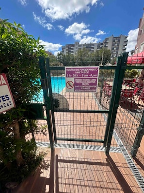 A pool area with a sign indicating operating hours and a no towel policy. - Charming duplex with a terrace and a view of the pool, 200 m from the beach (Portimão)