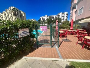 A gated entrance to a residential area with a swimming pool, outdoor seating area, and a sign indicating private access for residents. - Charming duplex apartment with a terrace and a view of the pool, 200 m from the beach (Portimão)
