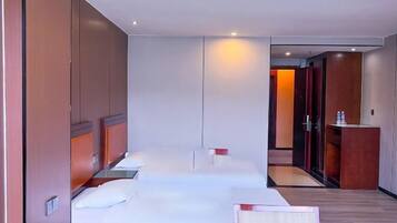 A hotel room with a large bed, a bedside table, a mirror, and a wardrobe.