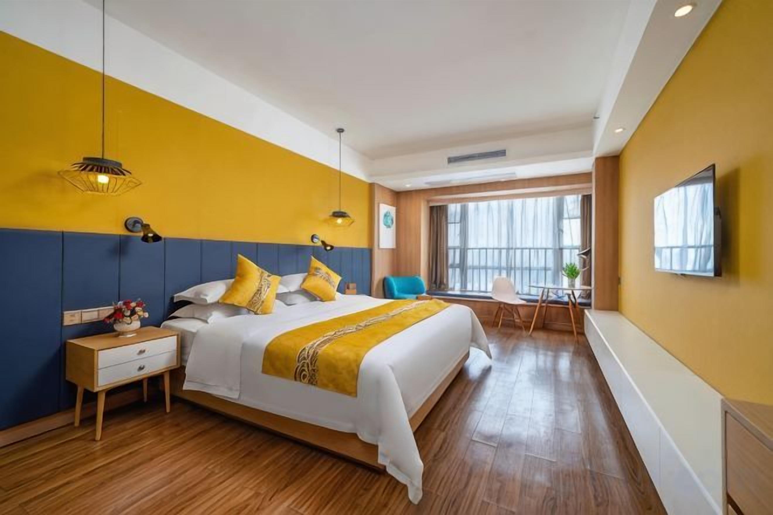 Una habitación de hotel con una cama grande, una mesita de noche y un televisor en la pared.