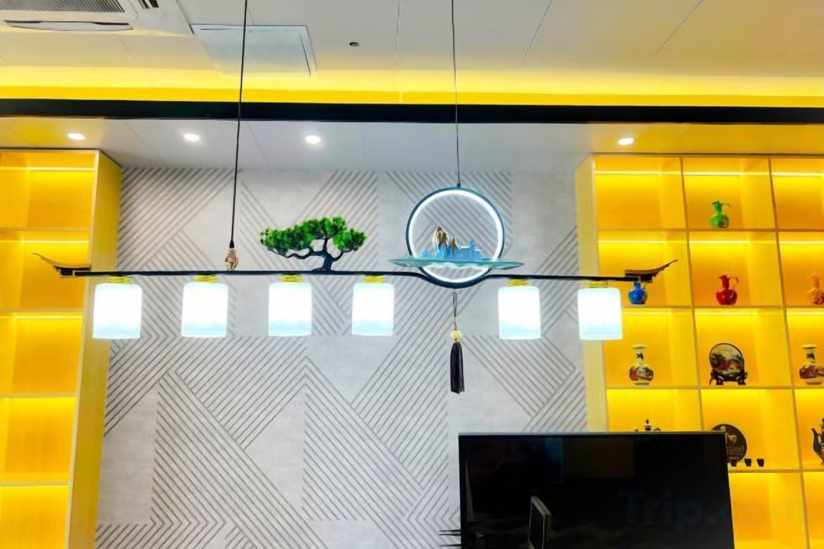 Zona de recepción con diseño moderno, que presenta una pared con patrón geométrico, un mostrador de recepción y una exhibición de objetos decorativos.