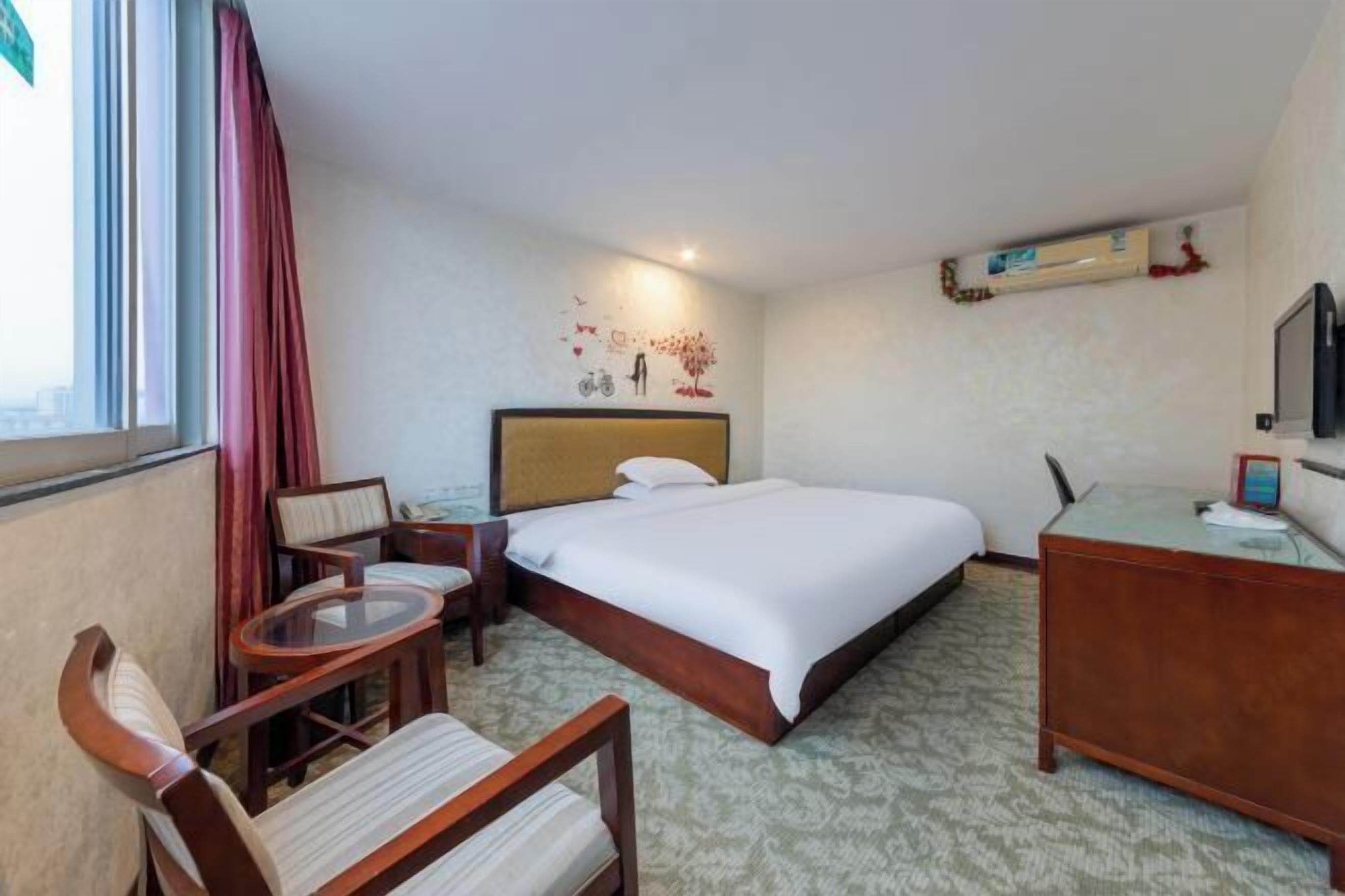 Een hotelkamer met een bed, bureau, stoel, klein tafeltje en televisie.