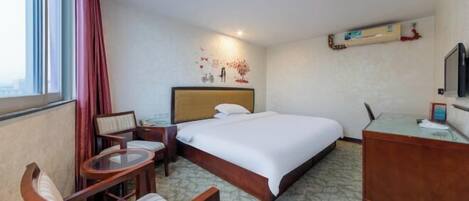 Een hotelkamer met een bed, bureau, stoel, klein tafeltje en televisie.