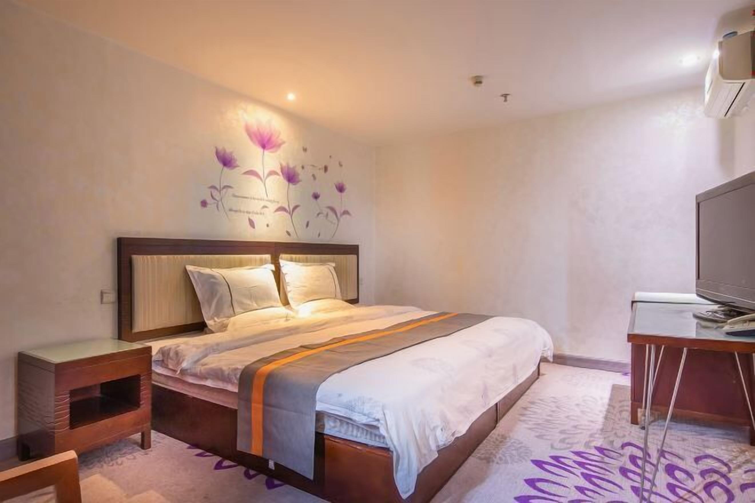 A hotel room with a bed, bedside table, and a TV.