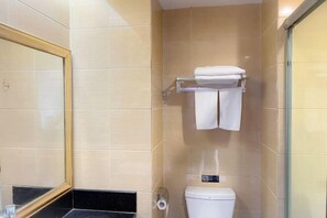 A bathroom with beige tiles, a white toilet, a towel rack with two towels, and a mirror with a gold frame. - Feiyang 88 Hotel (Guangzhou Panyu Plaza) (Guangzhou)