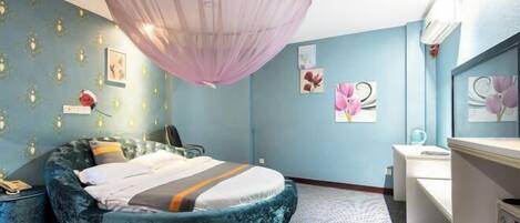 A bedroom with a round bed, a vanity, and a ceiling light fixture.