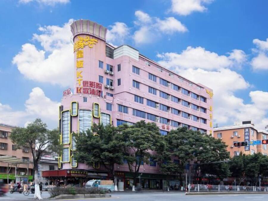 Un hotel de varios pisos con una fachada rosa distintiva, varios balcones y una entrada central.