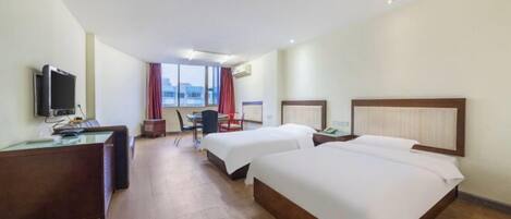 A hotel room with two beds, a desk with a computer, a television, and a window with curtains.