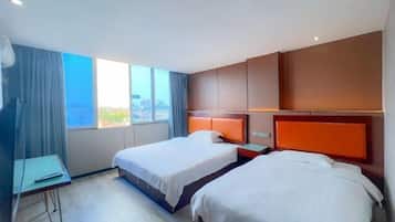 Ett hotellrum med två sängar, ett skrivbord och ett stort fönster med utsikt över staden.
