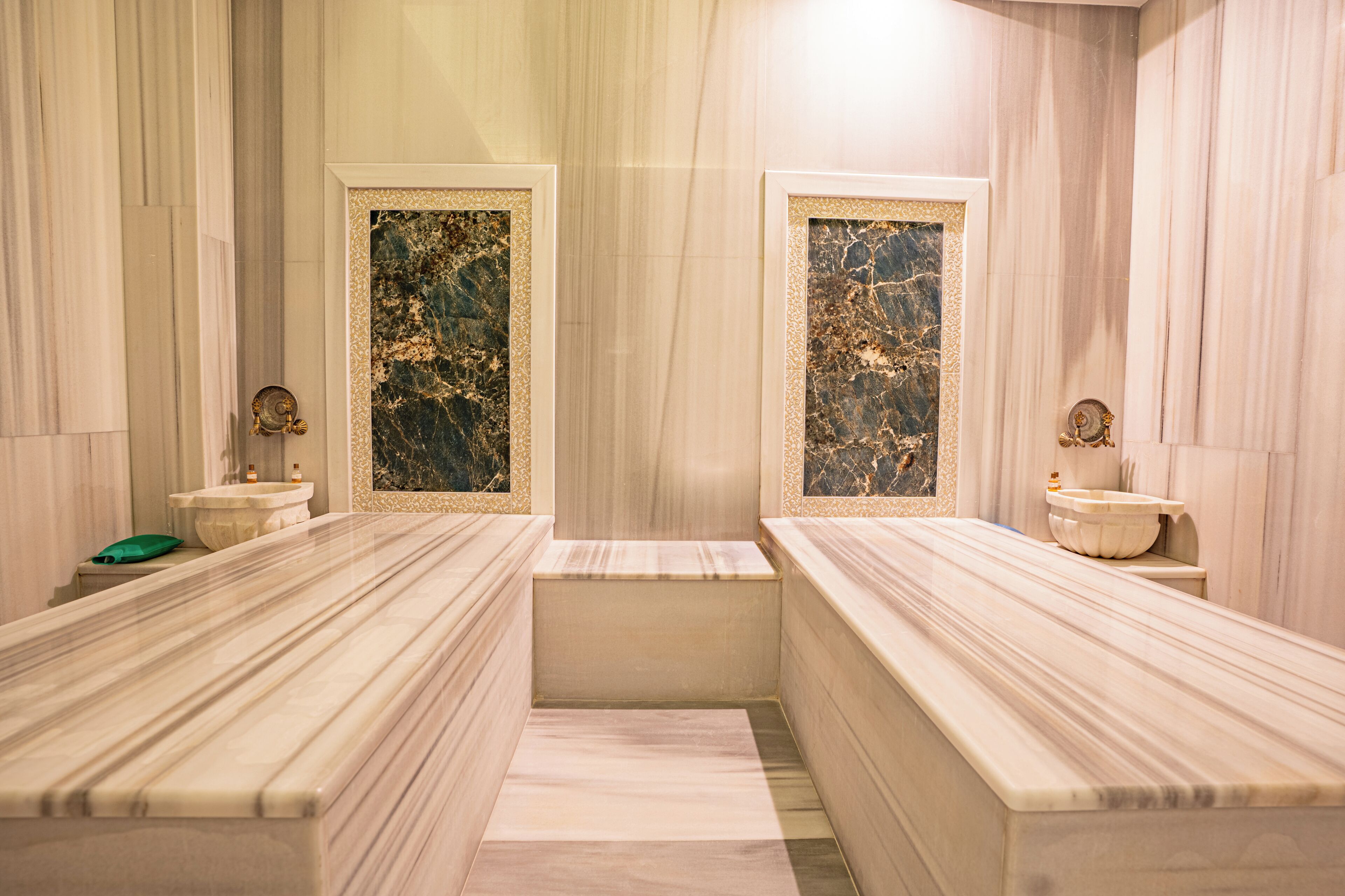 A bathroom with two marble sinks, a bathtub, and a mirror with a decorative frame.
