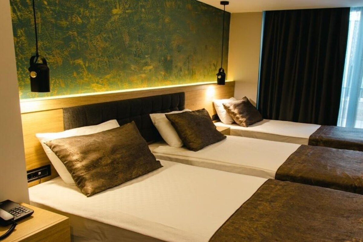 Habitación de hotel con dos camas, cabecero de madera, teléfono y pared con diseño texturizado.
