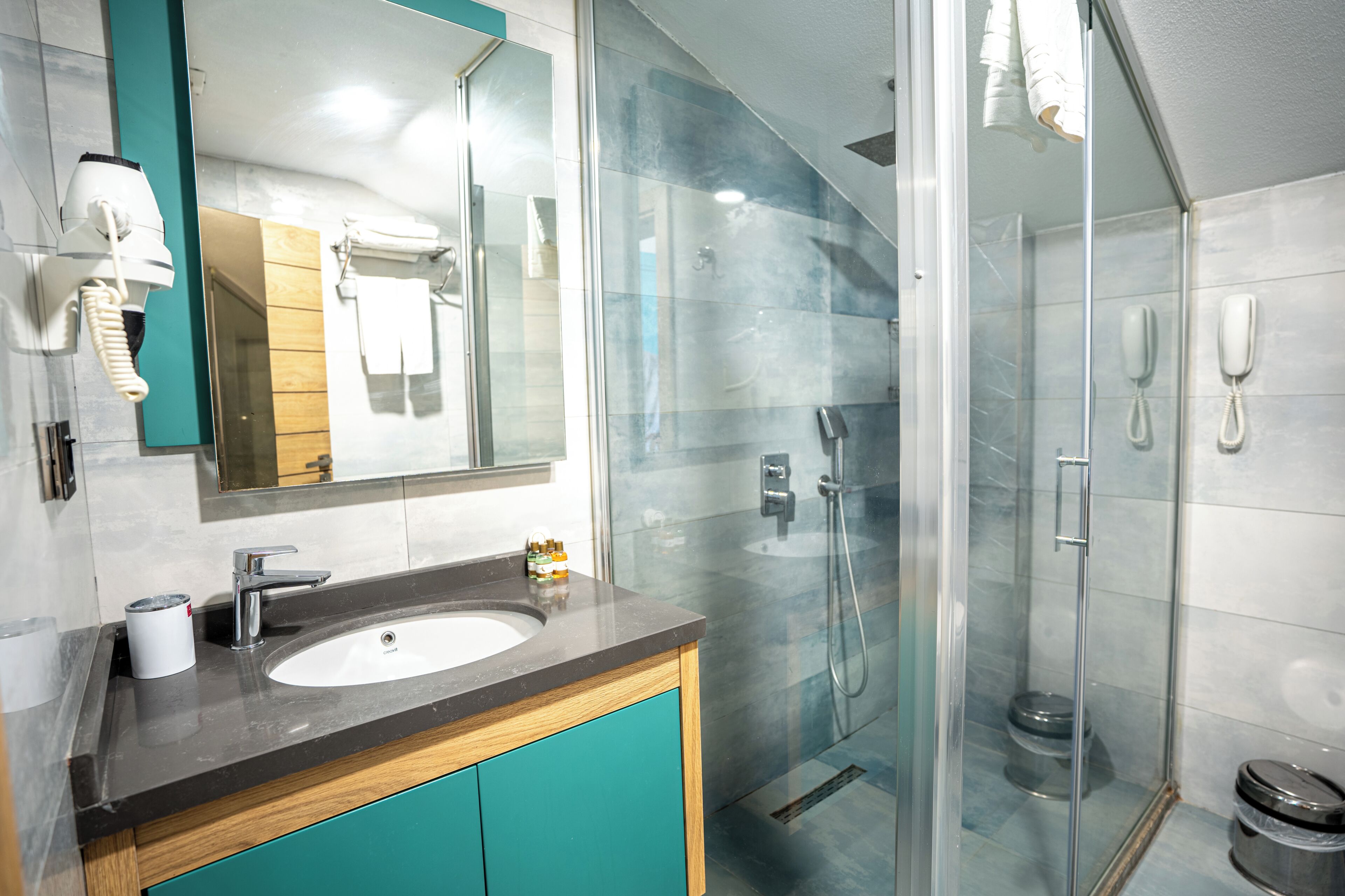 Une salle de bain moderne avec une douche à parois de verre, un lavabo avec un miroir et un téléphone.