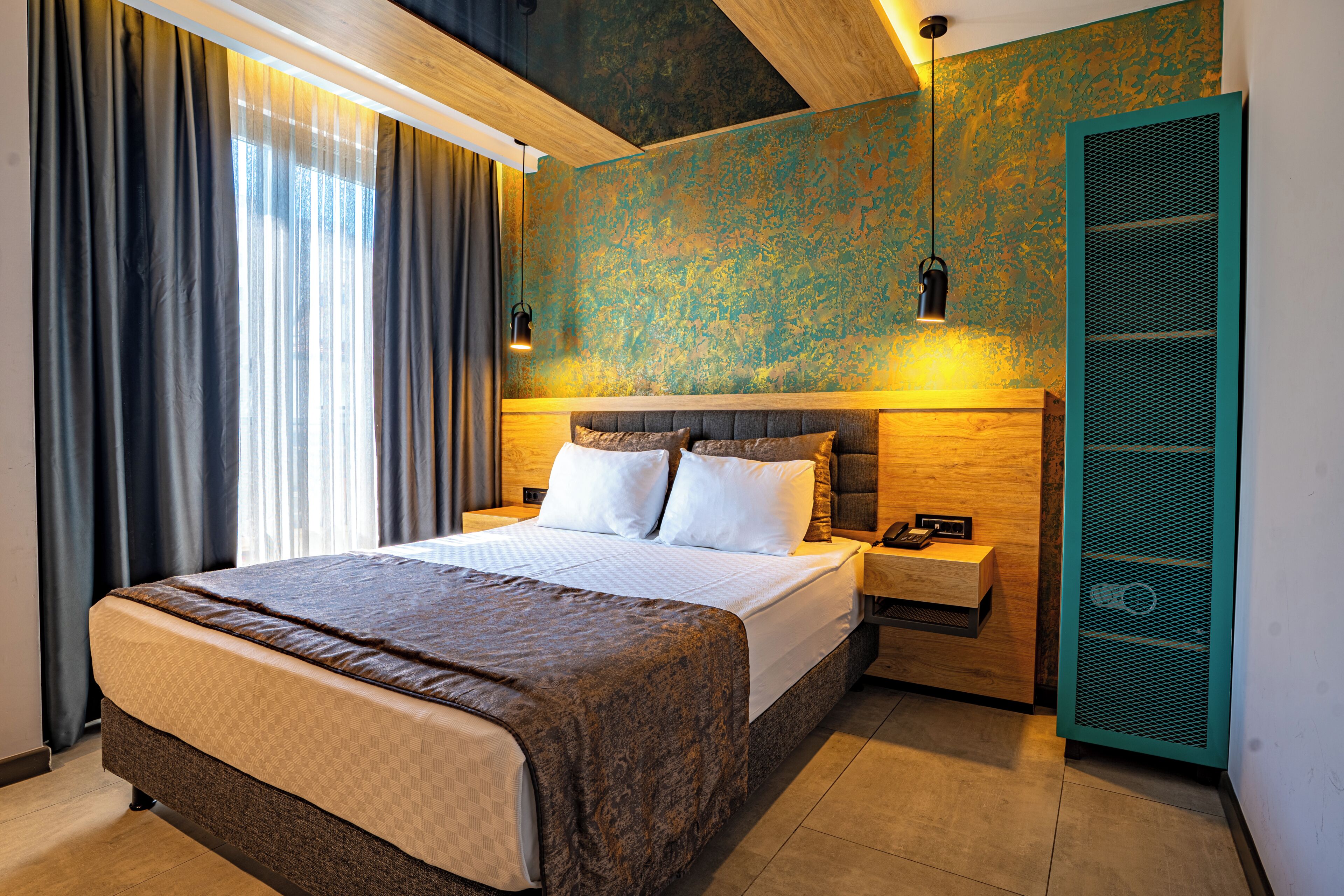 A hotel room with a large bed, a bedside table with a phone, and a wall-mounted light fixture.