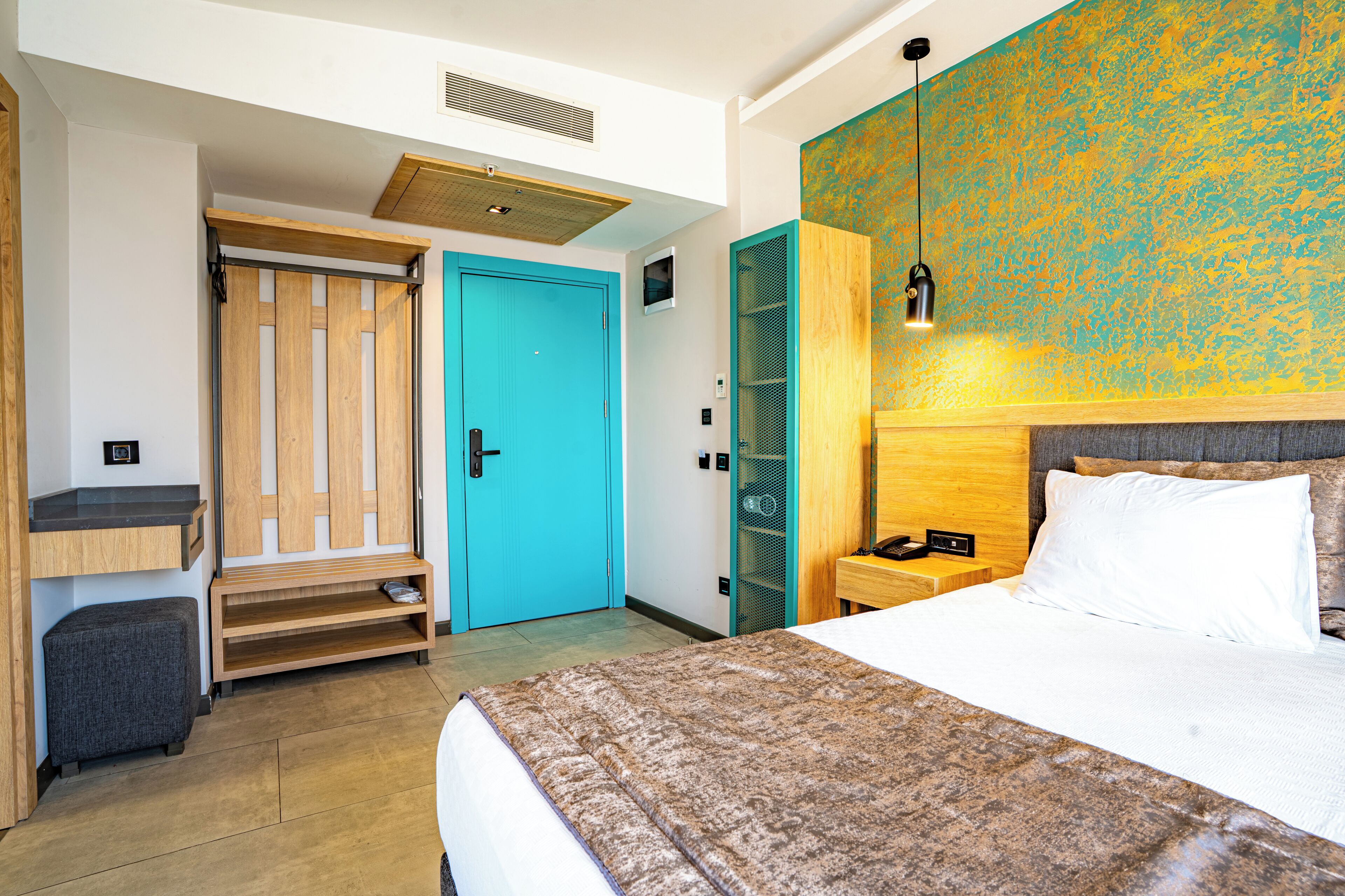 A hotel room with a bed, a desk, a wardrobe, and a bathroom.