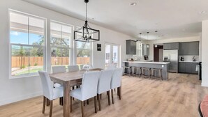 A spacious kitchen with a central island, large windows, and a dining area with a wooden table and chairs. - Mirasol Manor -sleeps up to 14! Minutes to Paso + SLO (Atascadero)