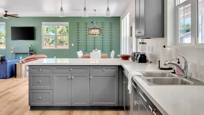 A modern kitchen with a large island, grey cabinets, and a view of the outdoors. - Mirasol Manor -sleeps up to 14! Minutes to Paso + SLO (Atascadero)