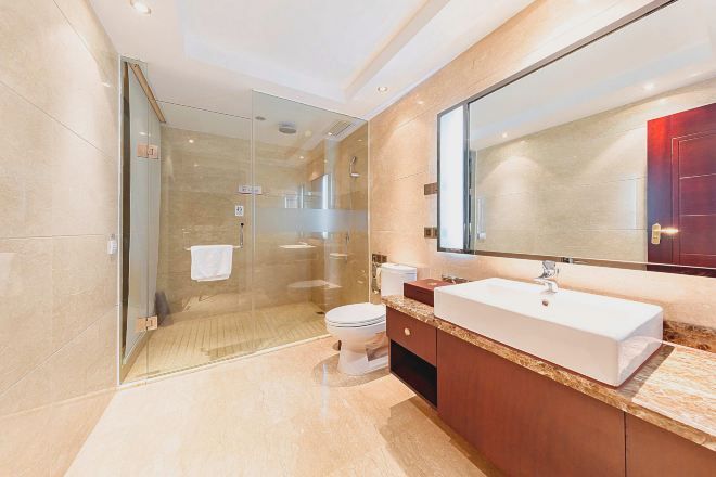 A modern bathroom with a glass-enclosed shower, a white sink, and a large mirror.