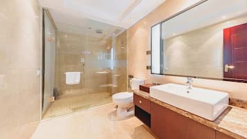 A modern bathroom with a glass-enclosed shower, a white sink, and a large mirror.