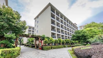 A multi-story hotel with a central courtyard, surrounded by well-maintained hedges and trees.