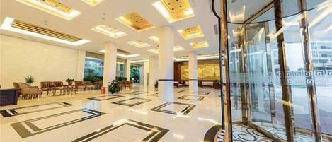 A spacious lobby with a high ceiling, large windows, and a central column.