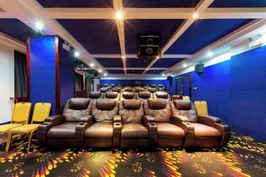 A theater room with rows of leather recliner seats, a ceiling-mounted projector, and a patterned carpet. - Jinqiu Holiday Hotel (Shanghang)