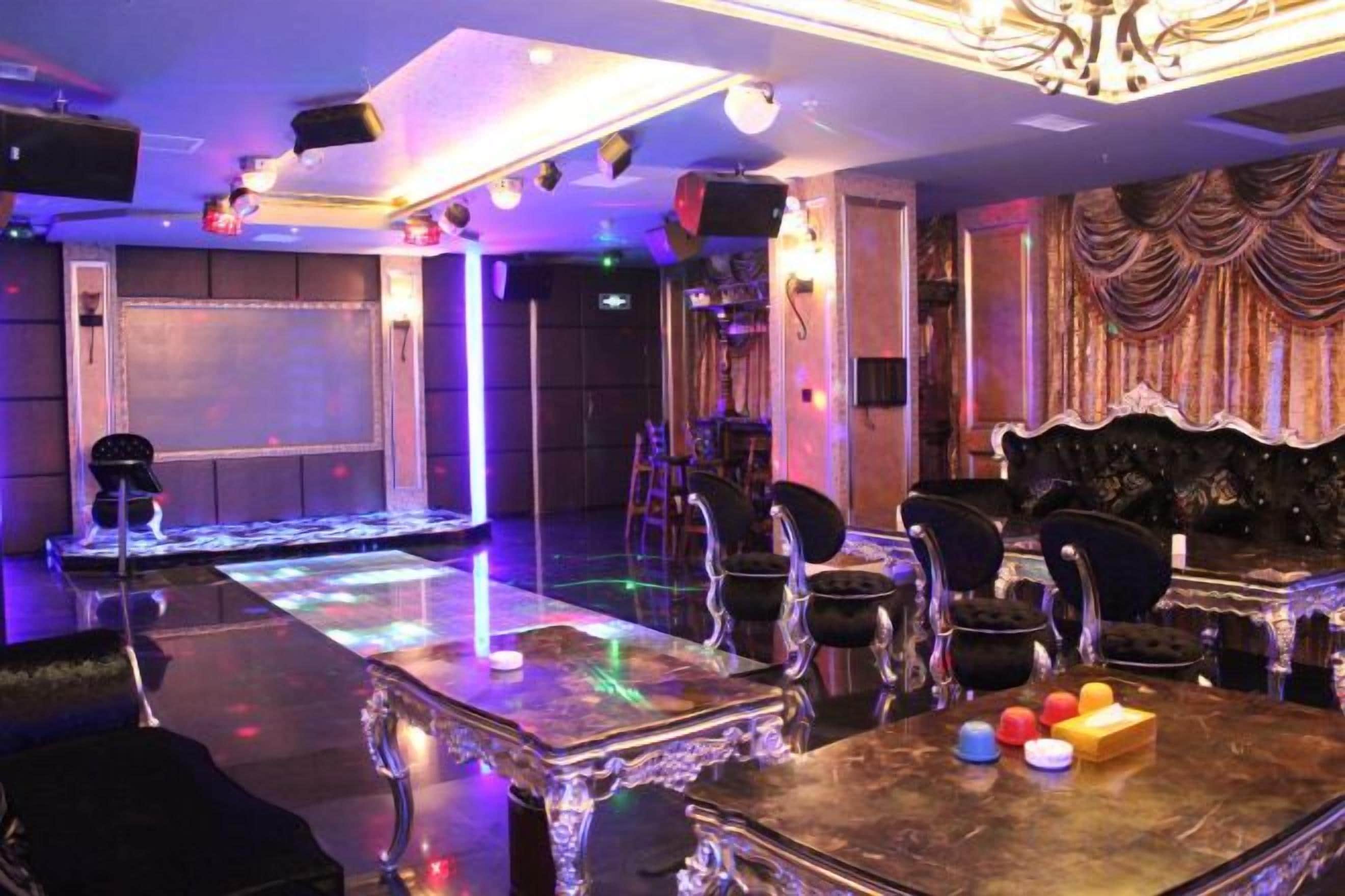 Una sala tenuemente iluminada con un escenario, mesas, sillas y una zona de bar.