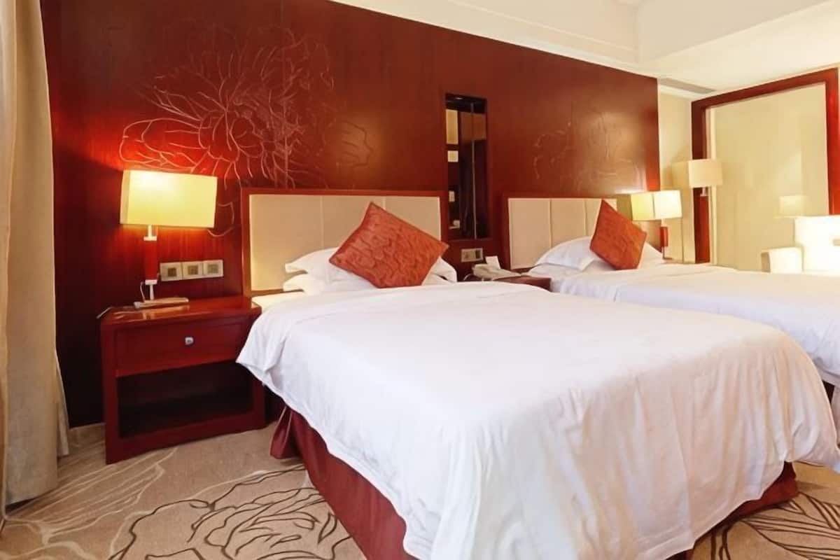 Habitación de hotel con dos camas, una mesita de noche, una lámpara y un espejo.