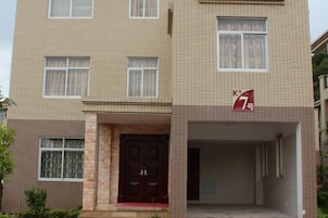 Un edificio residencial de varios pisos con fachada de tejas, una entrada central con una puerta oscura y un cartel que indica el número 7.